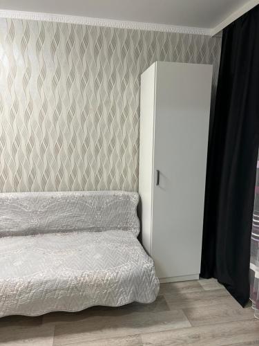 a bedroom with a bed and a white refrigerator at Апартаменты Экибастуз in Ekibastuz