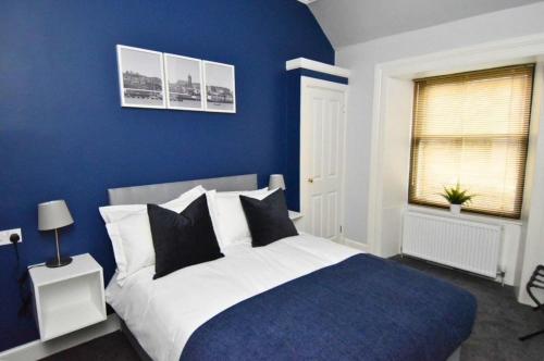 a blue bedroom with a bed with black and white pillows at The Kempock in Gourock