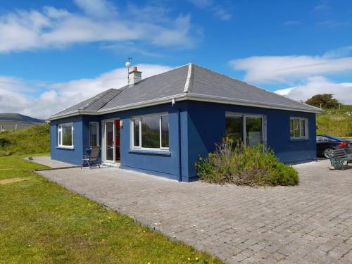 una casa blu in un campo con una macchina di Sandhill, a Mulranny