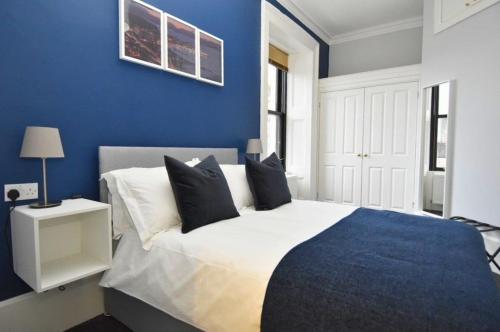 a blue bedroom with a large bed with black pillows at The Shore in Gourock