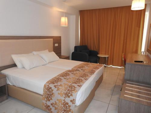 Habitación de hotel con cama y silla en Corfu Hotel, en Ayia Napa