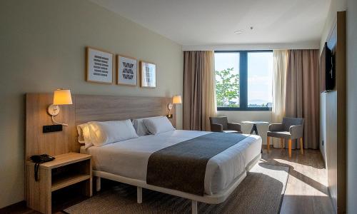 um quarto de hotel com uma cama e uma grande janela em Aparthotel Attica 21 Vallés em Sabadell