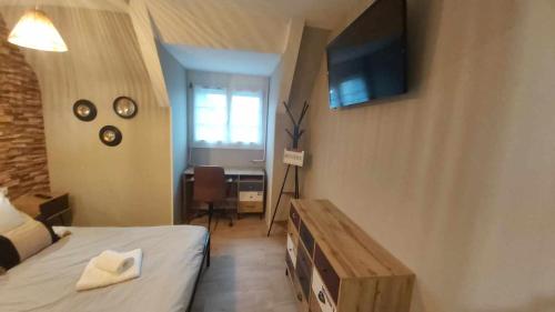 een slaapkamer met een bed, een bureau en een televisie bij La Renaissance in Condé-sur-Noireau