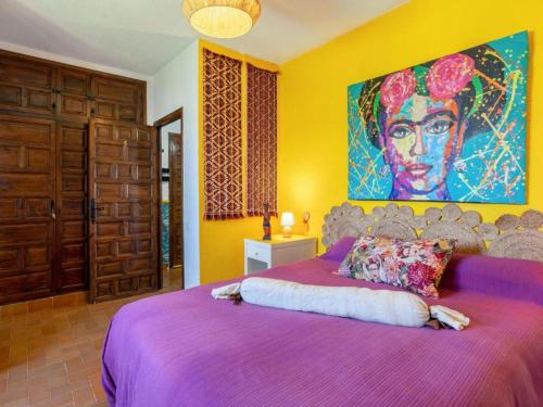 a bedroom with a purple bed with a large painting on the wall at VIVA la FRIDA KAHLO in Retamar