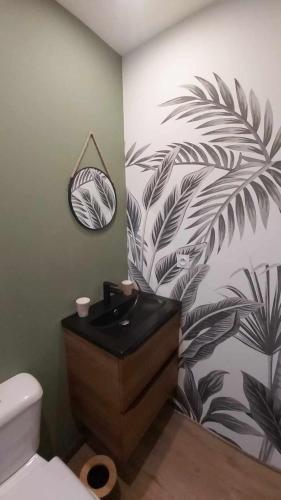 une salle de bain avec un lavabo noir et un mur végétal dans l'établissement La Renaissance, à Condé-sur-Noireau