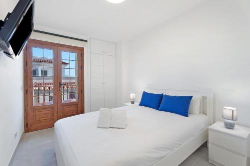 a white bedroom with a large white bed with blue pillows at Beautifull El Unicornio de Paula in Candelaria