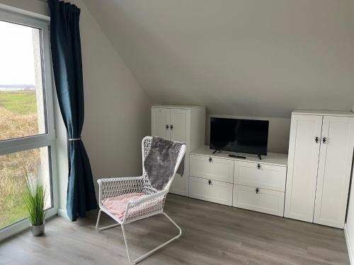 ein Wohnzimmer mit einem Stuhl und einem TV in der Unterkunft Ferienhaus Seepferd in Holnishof