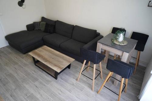 un salon avec un canapé noir et une table dans l'établissement Le Paisible • Garage Privatif • Traversant • Calme, à Châteauroux