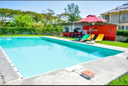 a swimming pool with two chairs and an umbrella at Lakewalk Cabin in Naivasha