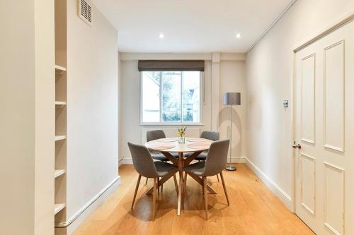 a dining room with a table and chairs and a window at Sloane Square terraced house in London