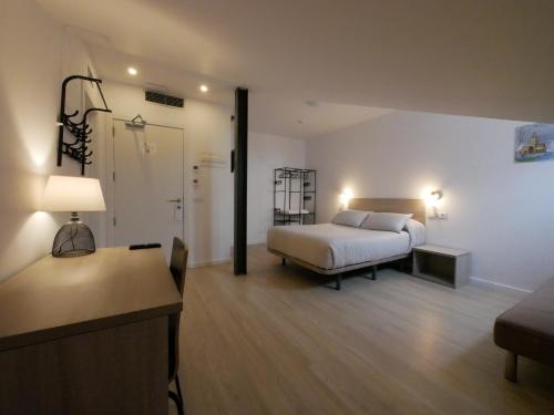a bedroom with a bed and a desk with a lamp at Hotel Myro in Gijón