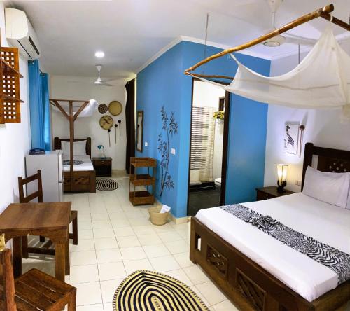 1 dormitorio con cama y pared azul en Highland Bungalows, en Nungwi