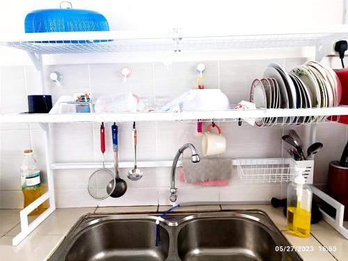 eine Küchenspüle mit Küchenutensilien und ein Regal darüber in der Unterkunft HOMESTAY NAFISAH in Tapah Road
