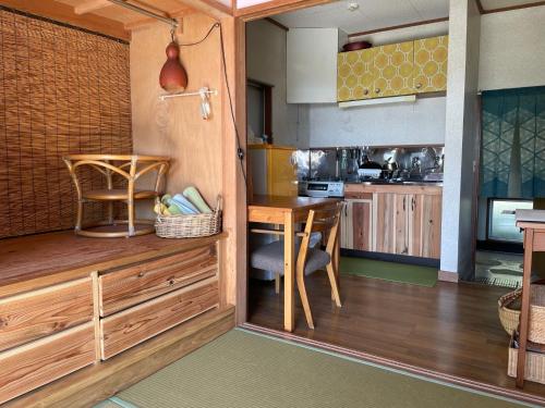 a kitchen with wooden cabinets and a table in it at Guesthouse Papaya in Shimoda