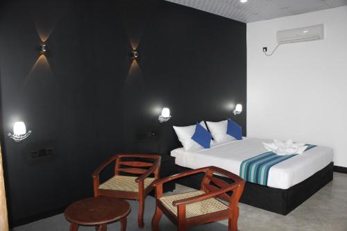ティッサマハーラーマにあるGreen Lake View Yala Resortのベッドルーム1室(ベッド1台、椅子2脚、テーブル付)