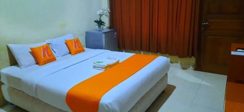 a bedroom with a large bed with orange and white pillows at Residence Duksina 2 By Shm in Kejayan