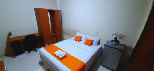 a bedroom with a bed with orange pillows and a desk at Residence Duksina 2 By Shm in Kejayan