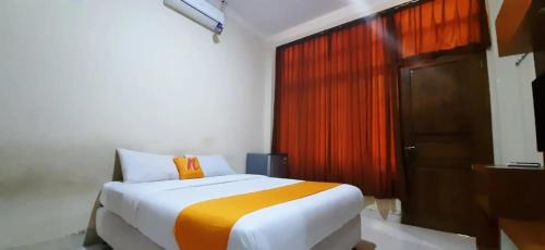 a bedroom with a bed with an orange pillow and a door at Residence Duksina 2 By Shm in Kejayan