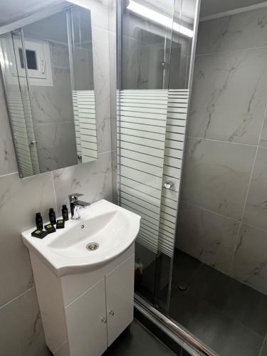 y baño blanco con lavabo y ducha. en Metropolitan Complex Apartment Faliro, en Pireo