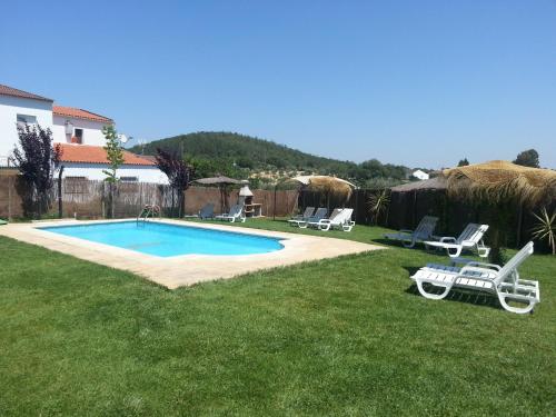 un patio con piscina, sillas y una casa en Casa Rural Sierra San Mamede, en La Codosera