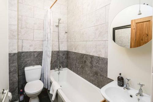 a bathroom with a tub and a toilet and a sink at Super Stylish 1BD Flat with Garden in Leytonstone in London