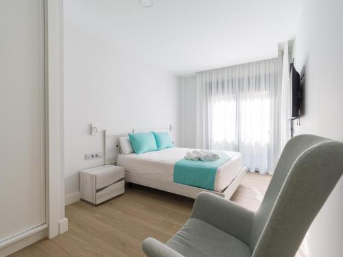 um quarto branco com uma cama e uma cadeira em Urban Square 3A5 By CanariasGetaway em Las Palmas de Gran Canaria