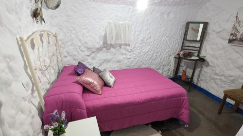 a bedroom with a purple bed with pillows on it at Cueva la Tita del Pan in Bácor