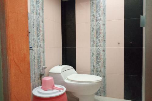 a bathroom with a white toilet and a pink container at OYO 93532 Kost Nian Syariah in Parepare