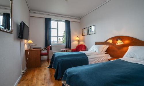 a hotel room with two beds and a television at Thon Partner Hotel Selbusjøen in Selbu