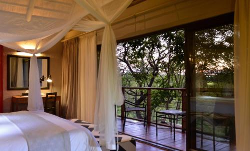 a bedroom with a bed and a balcony at Victoria Falls Safari Suites in Victoria Falls
