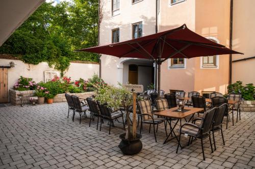 um pátio com uma mesa, cadeiras e um guarda-sol em Zum Dallmayr Hotel Garni em Berching