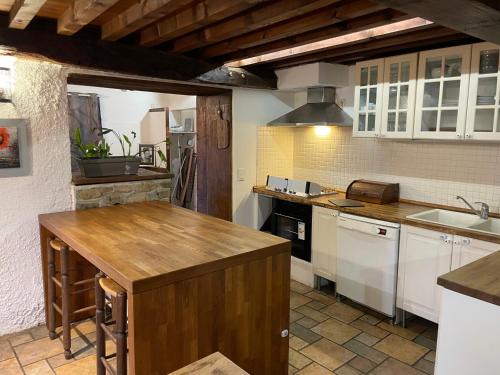 une cuisine avec des armoires blanches et un comptoir en bois dans l'établissement Gite de la Haure, Lourdes, à Lézignan