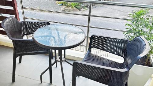 einen Glastisch und zwei Stühle auf dem Balkon in der Unterkunft AURIFLEX HOUSE in Krabi