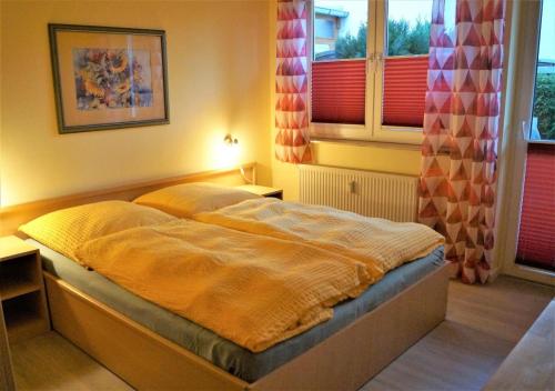 una camera con un letto in una stanza con finestre di Gemütliche Fewo in Strandnähe mit E-Grill, Haustiere erlaubt a Graal-Müritz