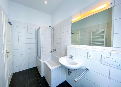 uma casa de banho branca com um lavatório e um espelho em Großzügige Fewo mit überdachter Terrasse, eigener Waschmaschine em Heringsdorf