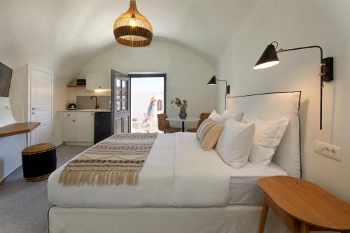 a bedroom with a large white bed and a kitchen at Lerion Luxury Villas in Akrotiri