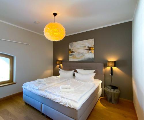 a bedroom with a white bed with a yellow light at Moderne Fewo mit Balkon, hochwertig in Heringsdorf