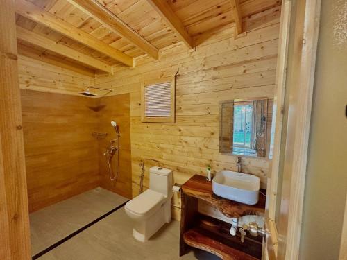 a wooden bathroom with a toilet and a sink at The Nine Beach Resort in Canacona