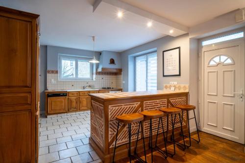 une cuisine avec un îlot et des tabourets de bar dans l'établissement Gaillarde - Maison pour 8 avec grand jardin, à Brive-la-Gaillarde