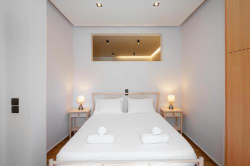 Un dormitorio con una gran cama blanca con dos lámparas. en Rene Luxury Apartment, en Zakynthos