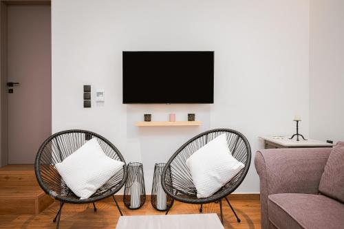 2 sillas de mimbre en una sala de estar con TV. en Rene Luxury Apartment, en Zakynthos