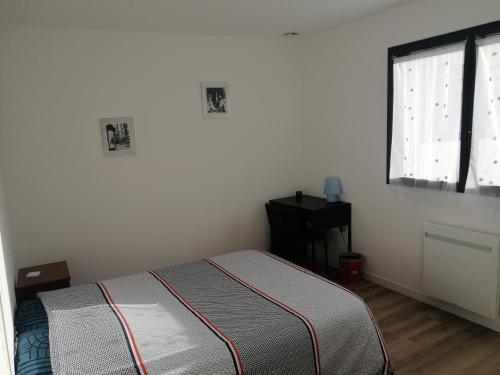 um pequeno quarto com uma cama e uma janela em Chambre chez l'habitant em Vitré