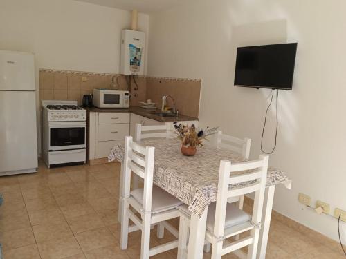 cocina con mesa con sillas blancas y TV en Jacarandá- A 50 mts de la av principal- Planta baja- Casa o Departamento en Federación