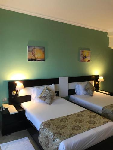 Moreno Resort and Spa في الغردقة: غرفة فندقية بسريرين وجدار أخضر