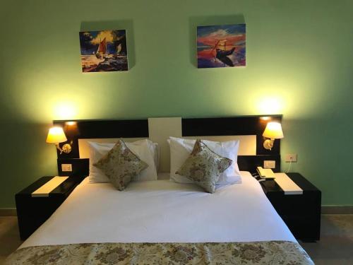 Moreno Resort and Spa في الغردقة: غرفة نوم بسرير ابيض كبير ومصباحين