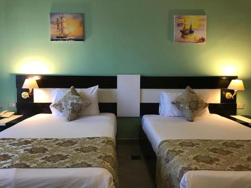 Moreno Resort and Spa في الغردقة: غرفة فندقية بسريرين وصورتين على الحائط