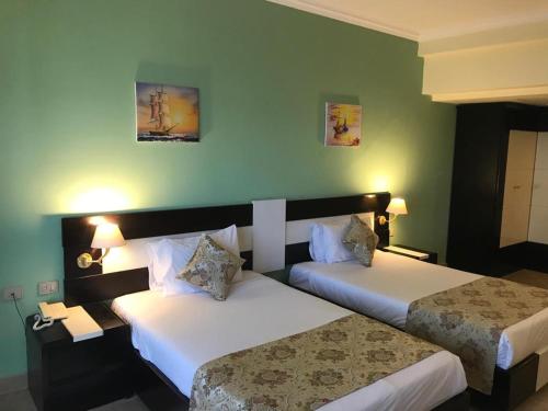 Moreno Resort and Spa في الغردقة: سريرين في غرفة فندق بجدران خضراء