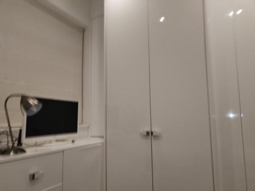 a room with white cabinets and a television on a shelf at single room available in Harpenden