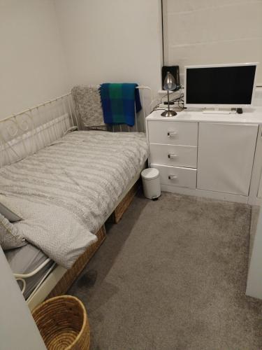 ein Schlafzimmer mit einem Bett und einer Kommode mit einem TV in der Unterkunft single room available in Harpenden