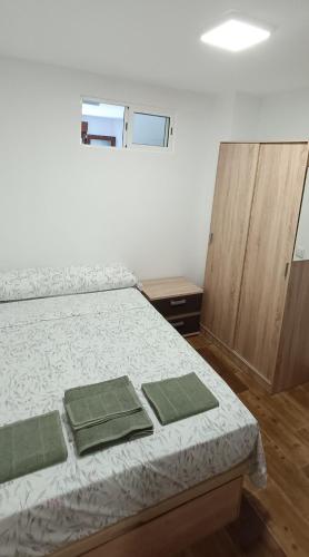 a bedroom with a bed with green towels on it at Apartamento Puente Romano in Salamanca